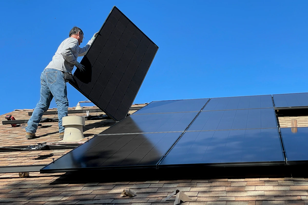 A worker positioning a rooftop solar panel